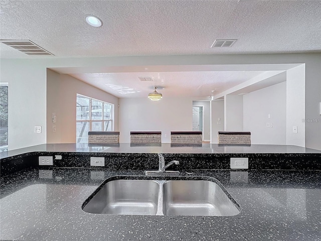 1176 Liberty Hall Dr, Kissimmee, FL 34746 - kitchen featuring a sink, dark stone countertops, a textured ceiling, open floor plan, and recessed lighting