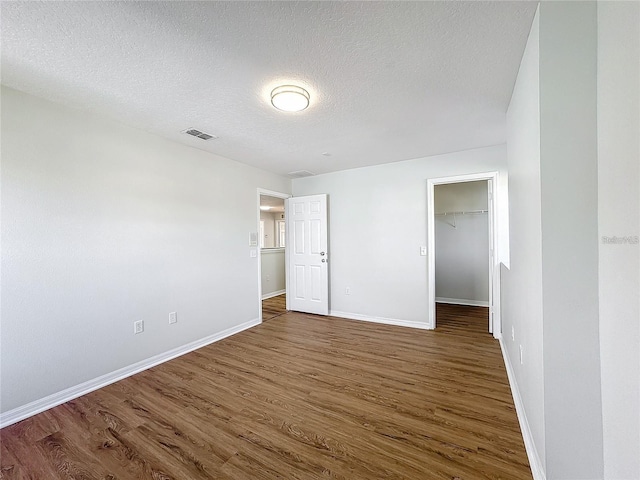 1176 Liberty Hall Dr, Kissimmee, FL 34746 - unfurnished bedroom featuring wood finished floors, baseboards, a textured ceiling, and a walk in closet