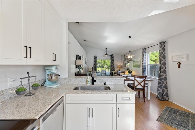 kitchen with a peninsula, stainless steel dishwasher, a sink, and white cabinetry