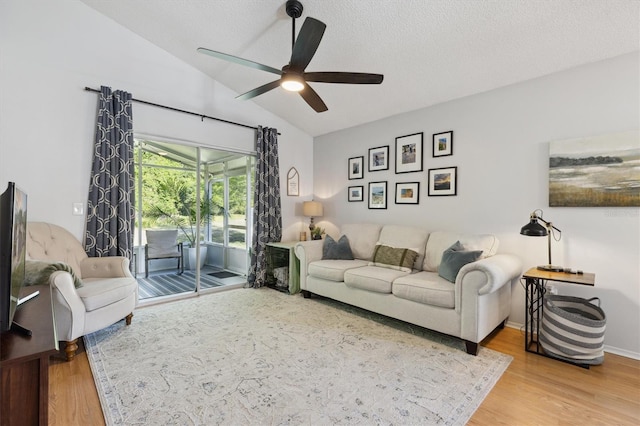 living area with ceiling fan, lofted ceiling, wood finished floors, and a textured ceiling