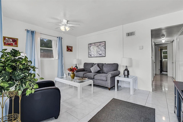 living area with baseboards, a ceiling fan, and visible vents