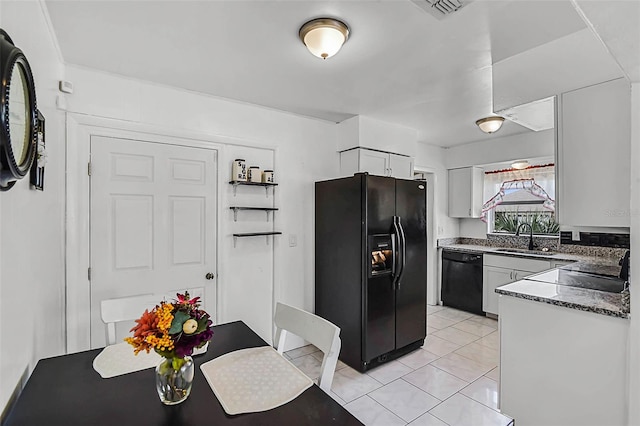 kitchen featuring light tile patterned floors, white cabinets, visible vents, black appliances, and a sink