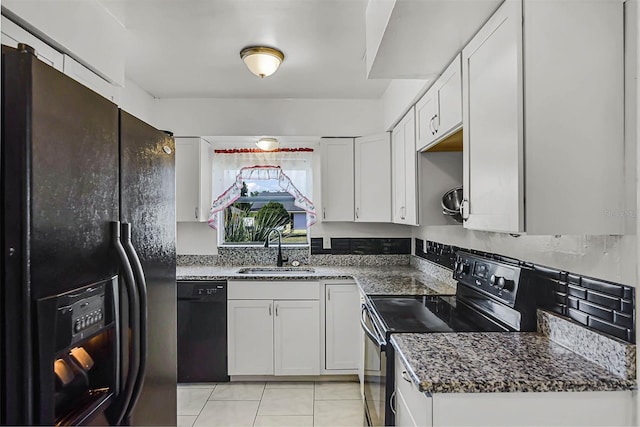 kitchen with dark stone countertops, a sink, black appliances, white cabinetry, and light tile patterned flooring