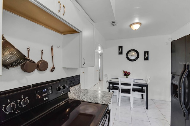 kitchen featuring light tile patterned floors, light stone countertops, white cabinets, visible vents, and black appliances