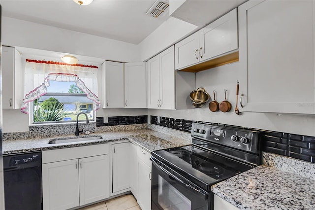kitchen featuring light stone counters, light tile patterned floors, white cabinetry, black appliances, and a sink