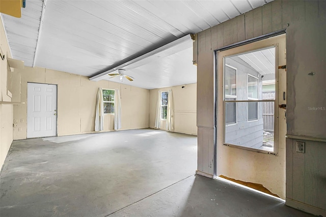 unfurnished room featuring concrete floors, beamed ceiling, and a ceiling fan