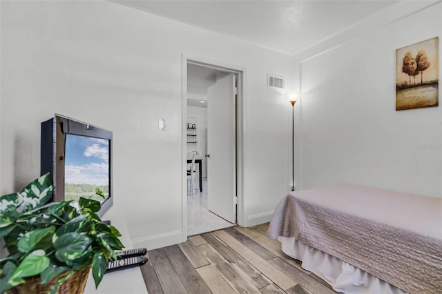bedroom with wood finished floors, baseboards, and visible vents