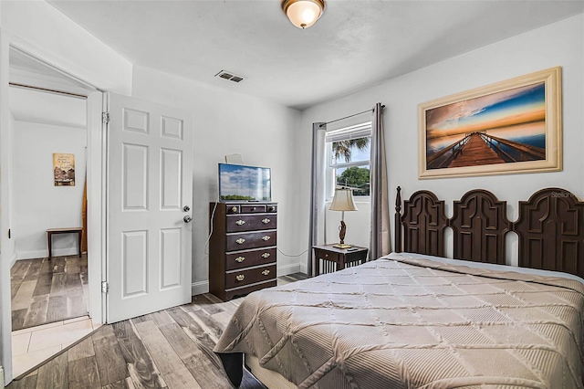 bedroom with wood finished floors, baseboards, and visible vents