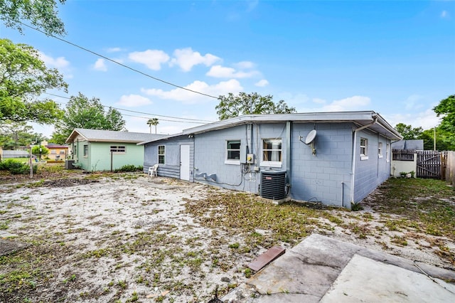 back of house with concrete block siding, fence, and central AC unit