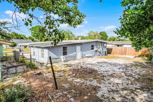 rear view of house with central AC unit and fence