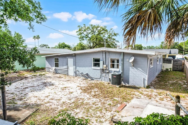exterior space featuring concrete block siding, fence, and central air condition unit