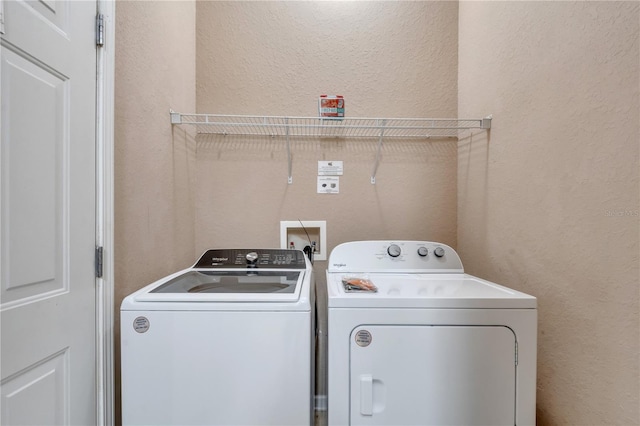 laundry room with a textured wall, washer and clothes dryer, and laundry area