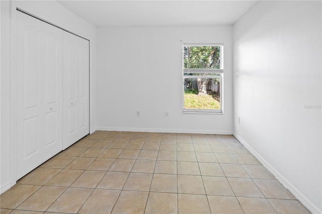12511 Lake Vista Dr, Gibsonton, FL 33534 - unfurnished bedroom featuring a closet, light tile patterned floors, and baseboards