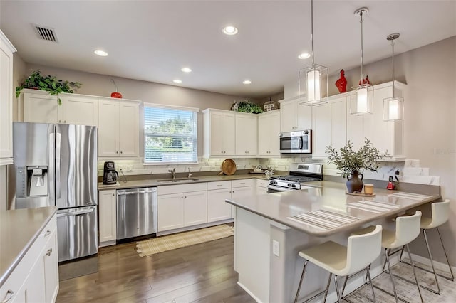 kitchen featuring tasteful backsplash, visible vents, a sink, a peninsula, and stainless steel appliances