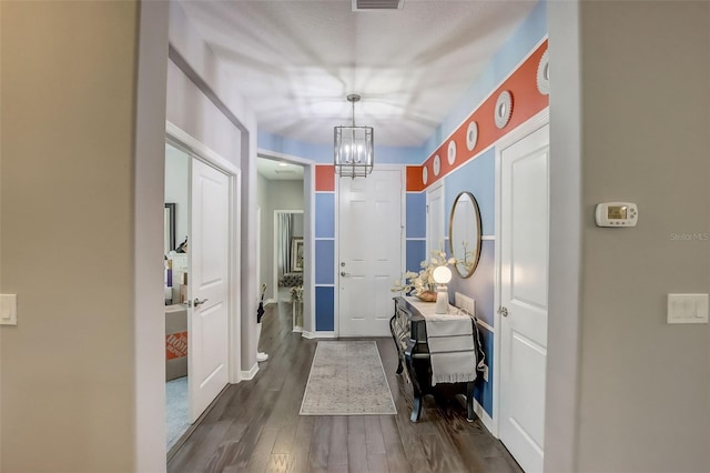 entryway featuring visible vents, a notable chandelier, dark wood-style floors, and baseboards