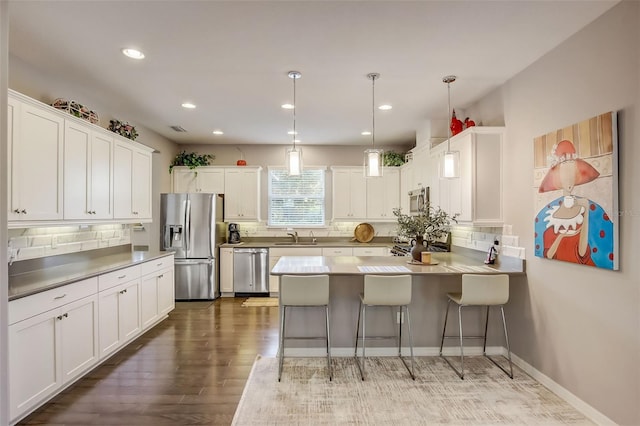 kitchen with tasteful backsplash, a peninsula, white cabinets, appliances with stainless steel finishes, and a sink
