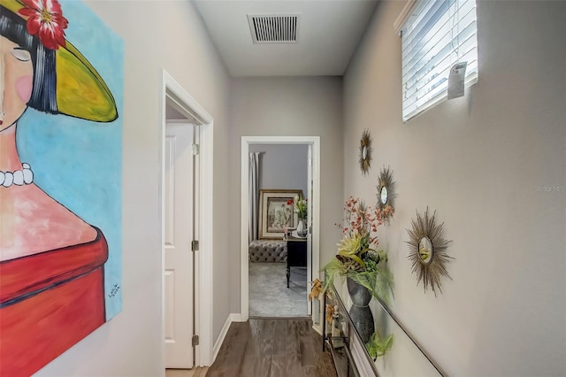 hallway featuring visible vents, baseboards, and dark wood finished floors