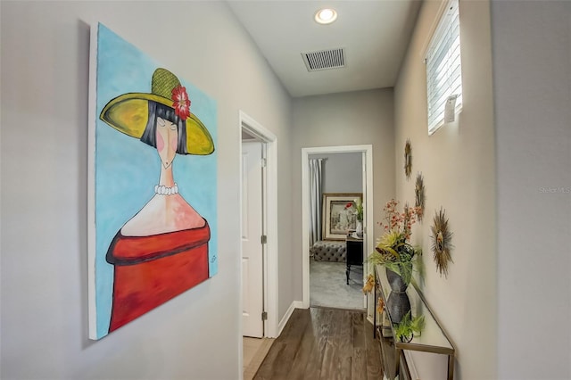 hallway with wood finished floors, baseboards, visible vents, and recessed lighting