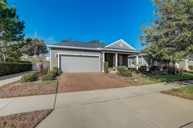 ranch-style home with an attached garage, covered porch, stucco siding, and decorative driveway