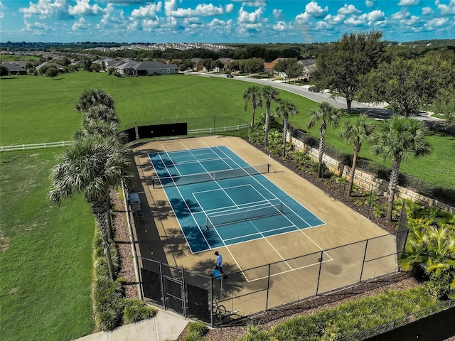 view of tennis court featuring a yard and fence