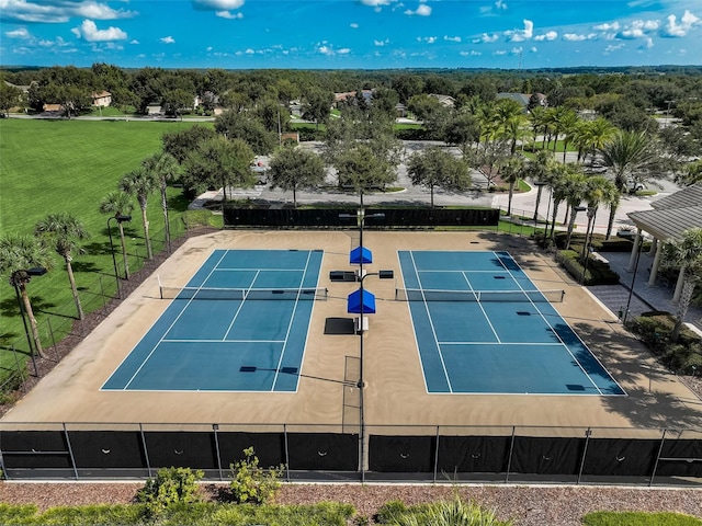 view of sport court with fence and a lawn