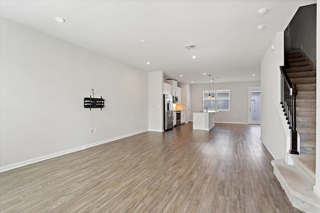 6165 Juneberry Way, Winter Garden, FL 34787 - unfurnished living room with visible vents, baseboards, wood finished floors, and stairs