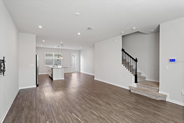 6165 Juneberry Way, Winter Garden, FL 34787 - unfurnished living room featuring baseboards, stairway, dark wood-type flooring, visible vents, and a sink