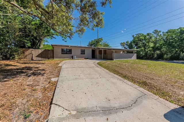 single story home featuring central AC unit, fence, a front lawn, an attached carport, and driveway