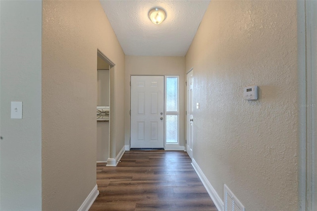 entryway featuring dark wood-style flooring, visible vents, and a textured wall
