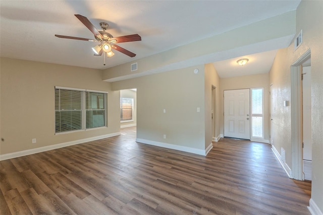 unfurnished room with dark wood-style flooring, visible vents, ceiling fan, and baseboards