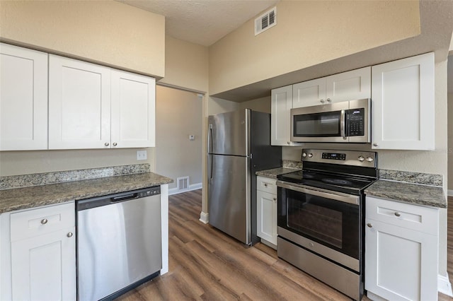 kitchen with white cabinets, appliances with stainless steel finishes, dark wood-style floors, and visible vents