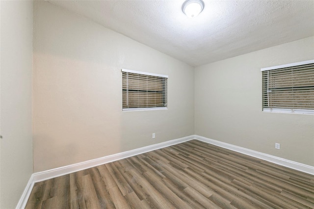 spare room featuring baseboards, vaulted ceiling, and wood finished floors