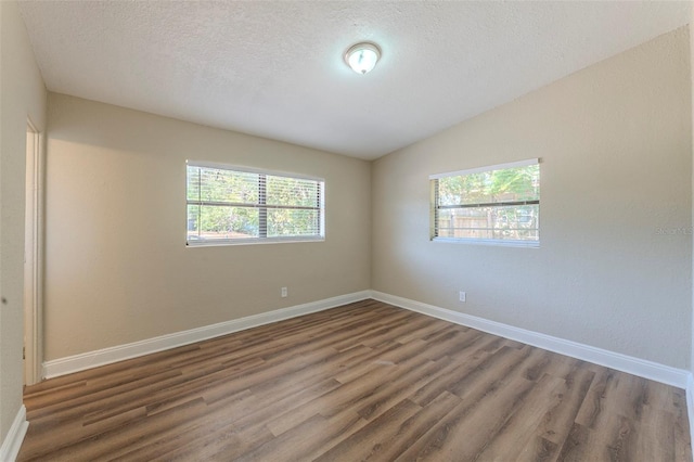 unfurnished room with baseboards, lofted ceiling, wood finished floors, and a healthy amount of sunlight