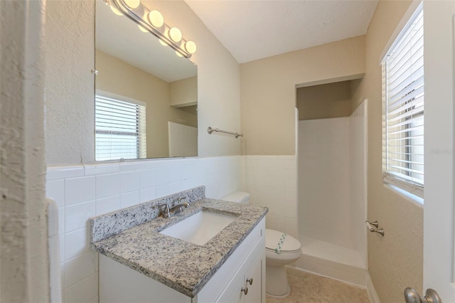 bathroom featuring vanity, tile patterned flooring, toilet, tile walls, and a stall shower