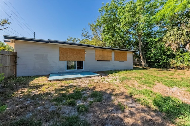 rear view of property with a yard, concrete block siding, fence, and a patio