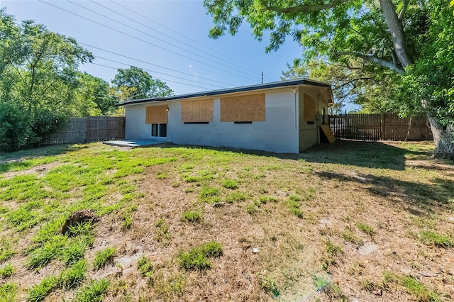 rear view of house with a fenced backyard and a lawn