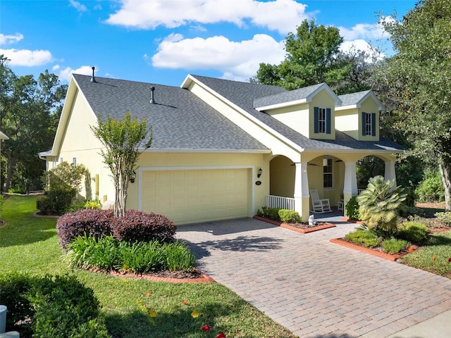 view of front of home with stucco siding, decorative driveway, an attached garage, a shingled roof, and covered porch