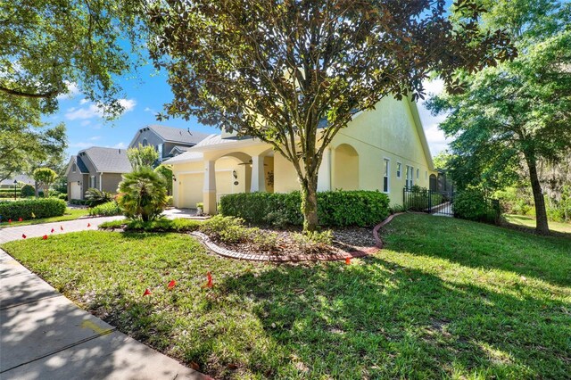 view of side of home featuring an attached garage, a yard, stucco siding, and fence