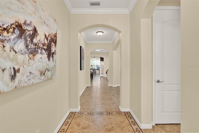 hallway with visible vents, baseboards, light tile patterned floors, arched walkways, and crown molding