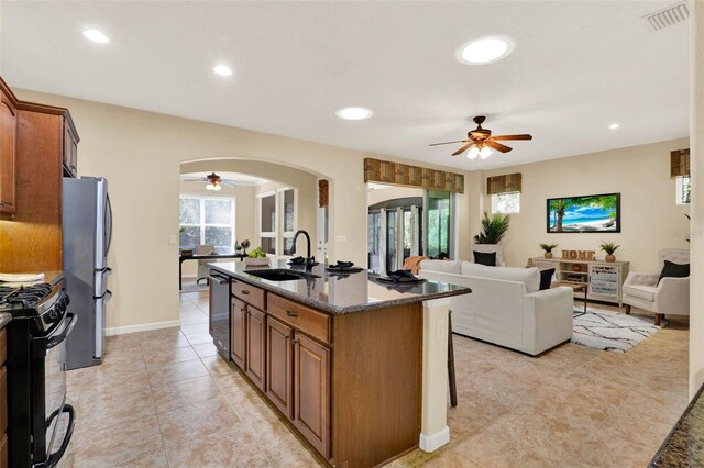 kitchen with arched walkways, a sink, freestanding refrigerator, a ceiling fan, and dishwashing machine