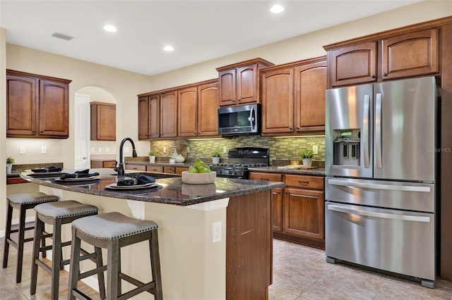 kitchen with tasteful backsplash, an island with sink, light tile patterned floors, visible vents, and stainless steel appliances
