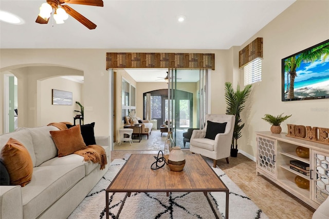 living area featuring arched walkways, baseboards, a ceiling fan, and light tile patterned flooring