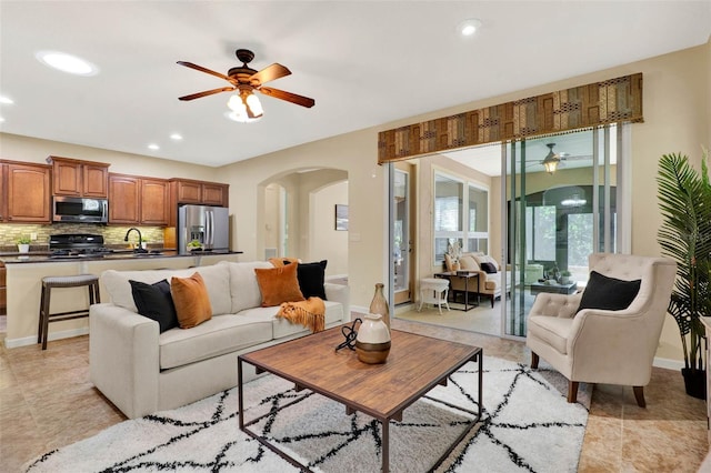 living area with arched walkways, a ceiling fan, recessed lighting, light tile patterned flooring, and baseboards