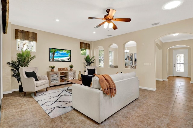 living area featuring light tile patterned floors, arched walkways, a ceiling fan, visible vents, and recessed lighting