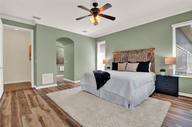 bedroom featuring arched walkways, visible vents, and wood finished floors
