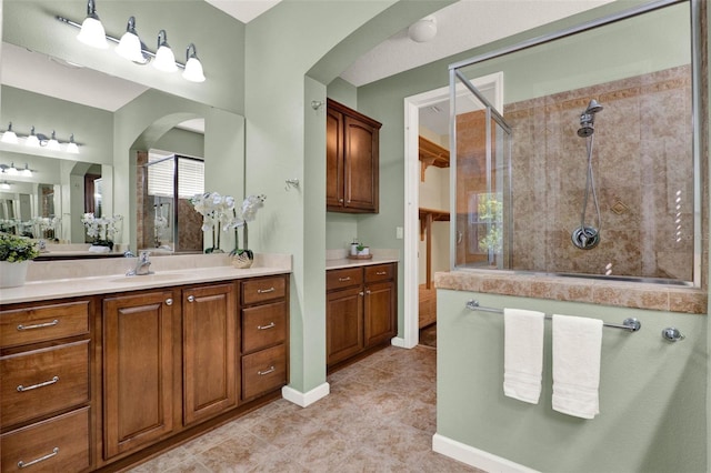 bathroom featuring tile patterned floors, a tile shower, vanity, and baseboards
