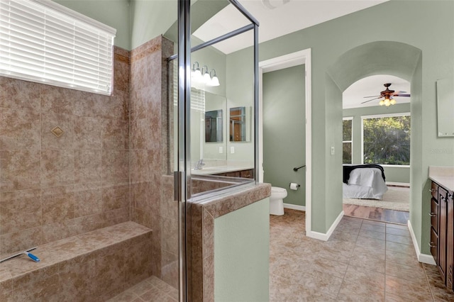 bathroom with vanity, a ceiling fan, toilet, a stall shower, and tile patterned floors