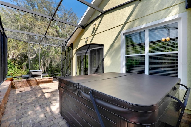 view of patio / terrace featuring a lanai and a hot tub