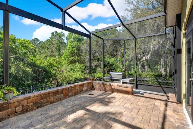 view of patio featuring a view of trees and a lanai