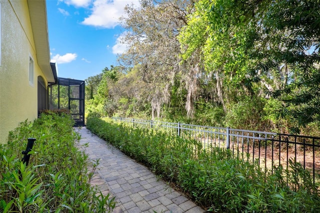 view of yard featuring fence and glass enclosure